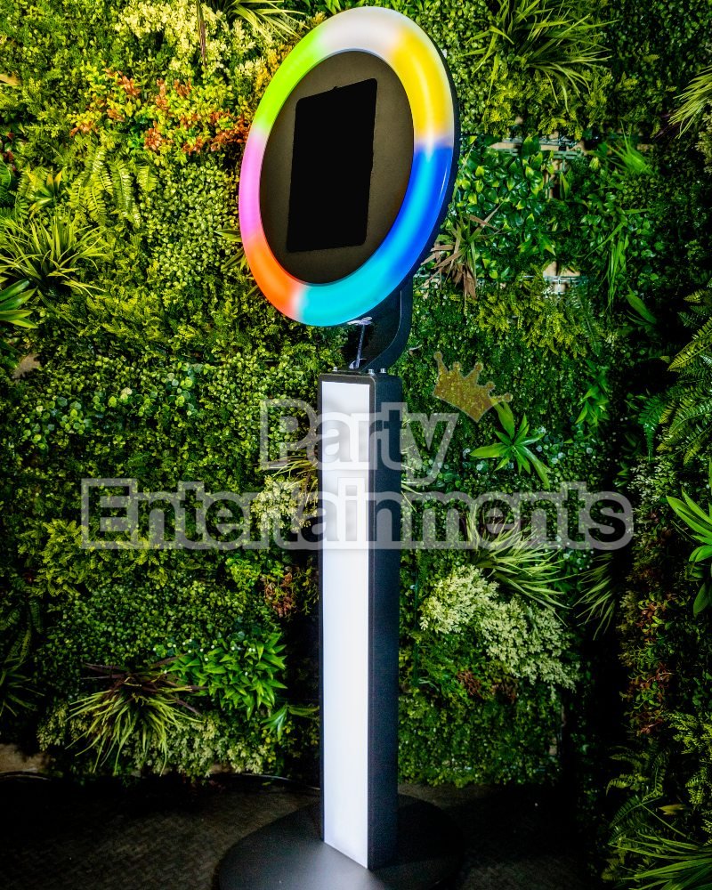 Multi rainbow coloured iPad Selfie Photo Booths against green fake background with different types of leaves