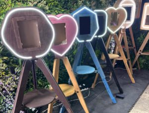 7 different Vintage Photo Booths in varying shapes and colours all Photo Booths to Buy UK against a green background.