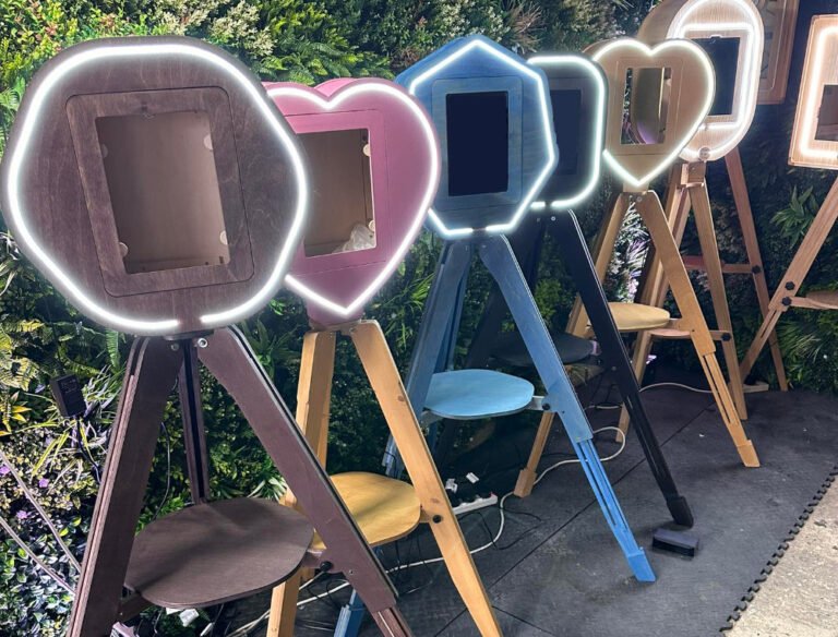 7 different Vintage Photo Booths in varying shapes and colours all Photo Booths to Buy UK against a green background.