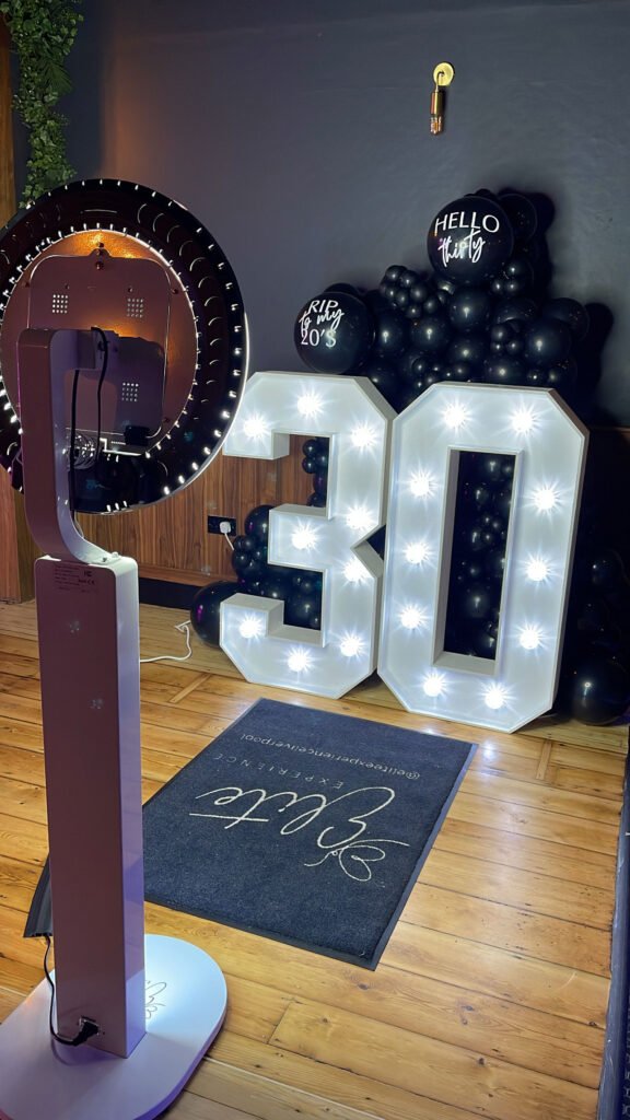 3oth birthday Photo Booth Hire showing large 30 numbers lit up and a white photobooth.