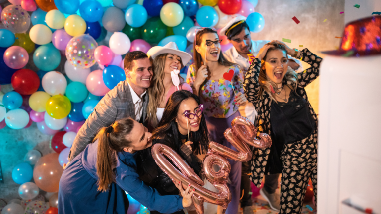 Group of people at a party posing for a photo booth with balloons behind them for a post on Are photo booths worth it?