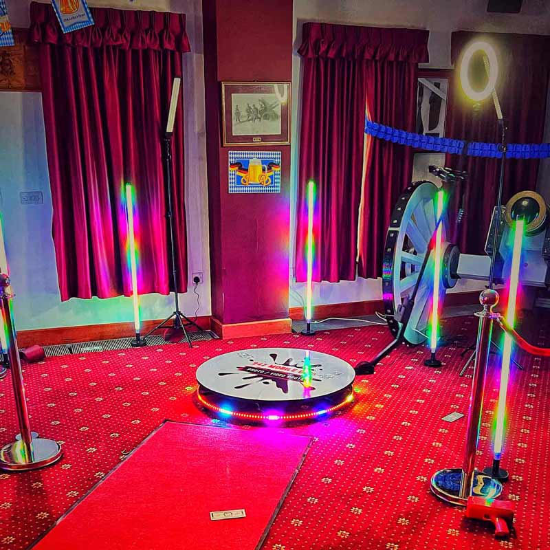 360 Photo Booth in a room with a bright red carpet. LED lights surrounding the booth